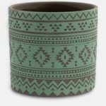 The Κασπώ Luvio Πράσινο is a round green ceramic pot adorned with brown geometric tribal patterns, such as triangles and diamonds, on its exterior.